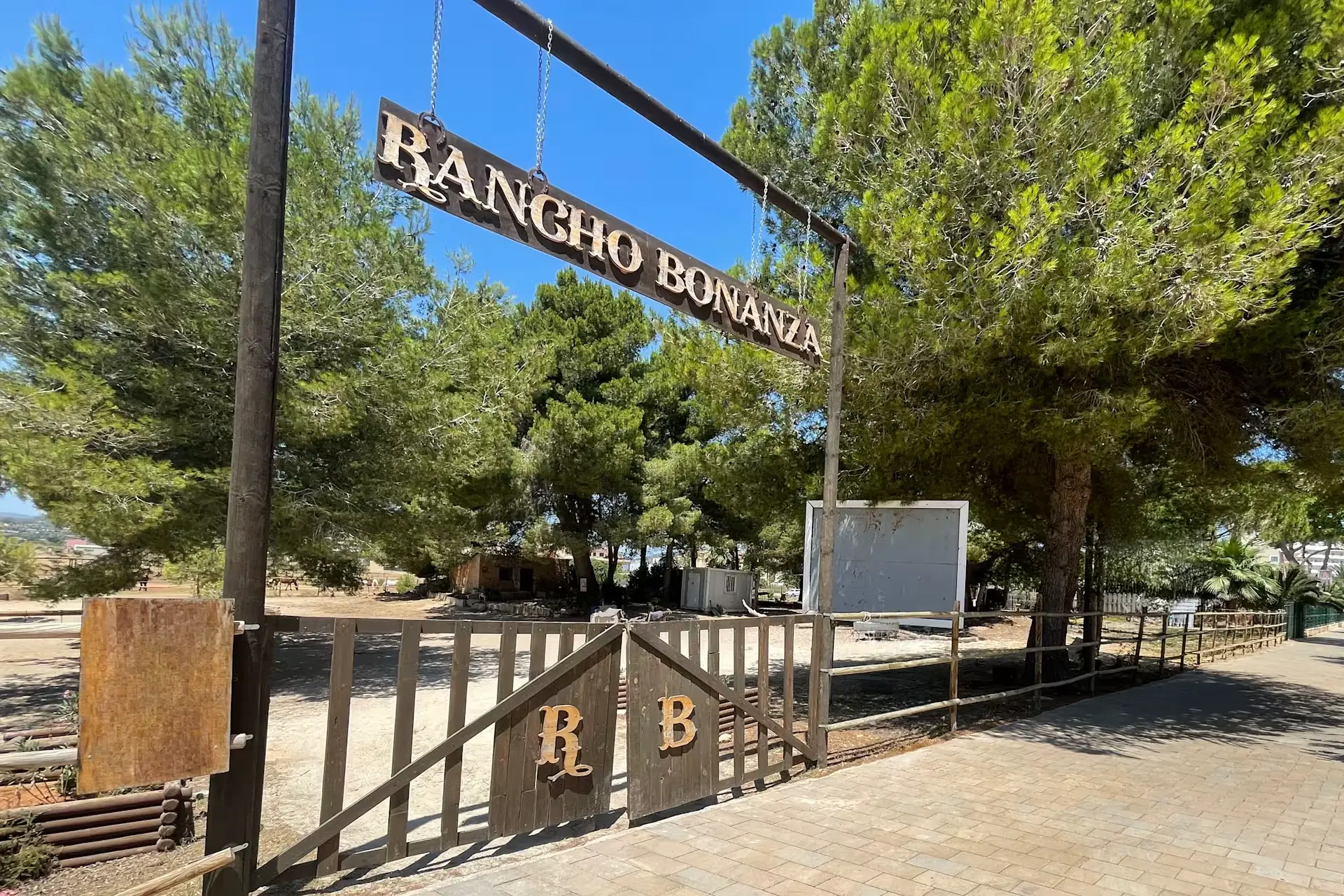 Wooden Rancho Bonanza entrance sign and gate among pine trees
